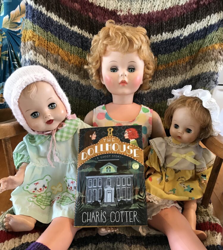 Dolls posed with a copy of The Dollhouse by Charis Cotter
